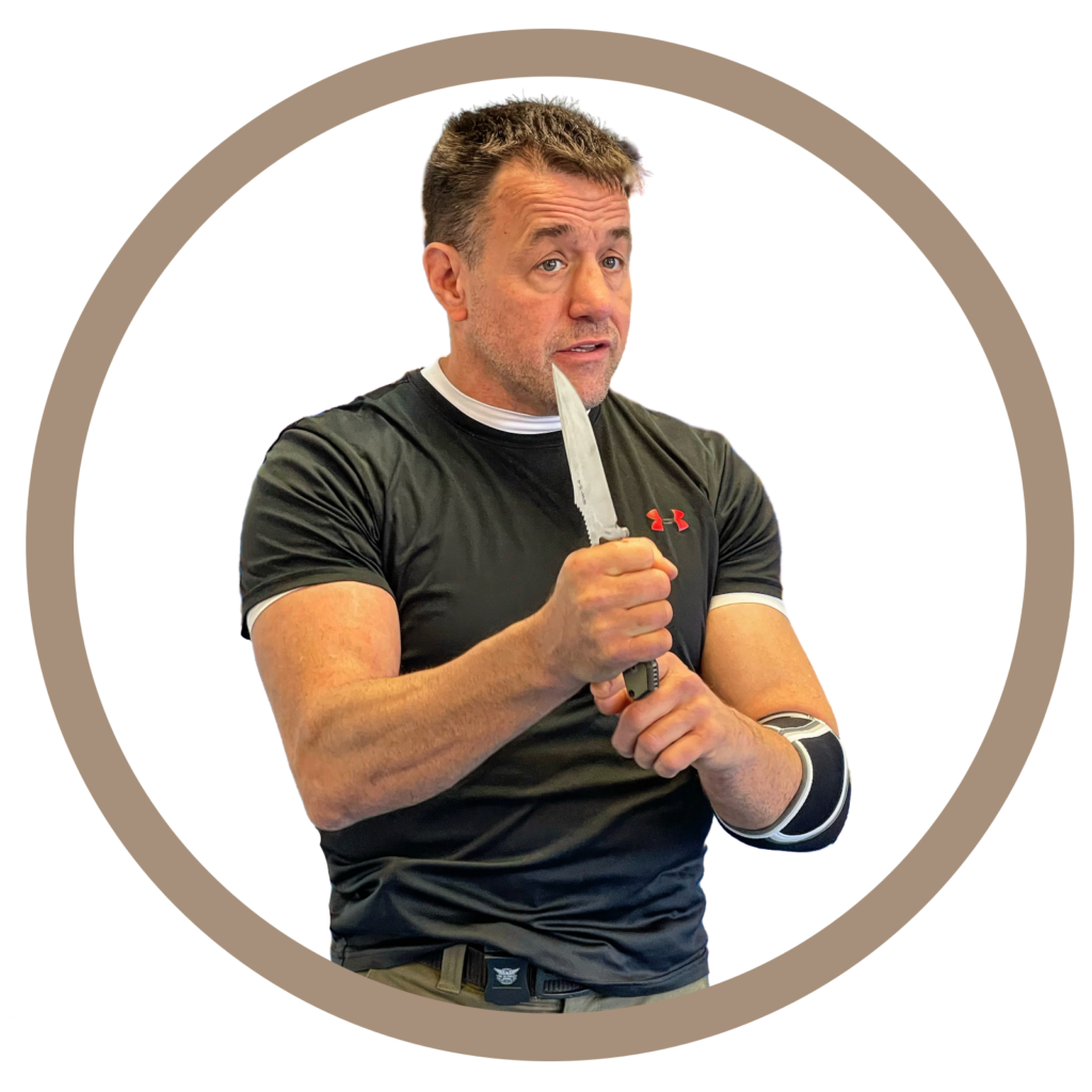 Sifu Alan Baker holding a fixed blade knife and teaching in front of a class. 