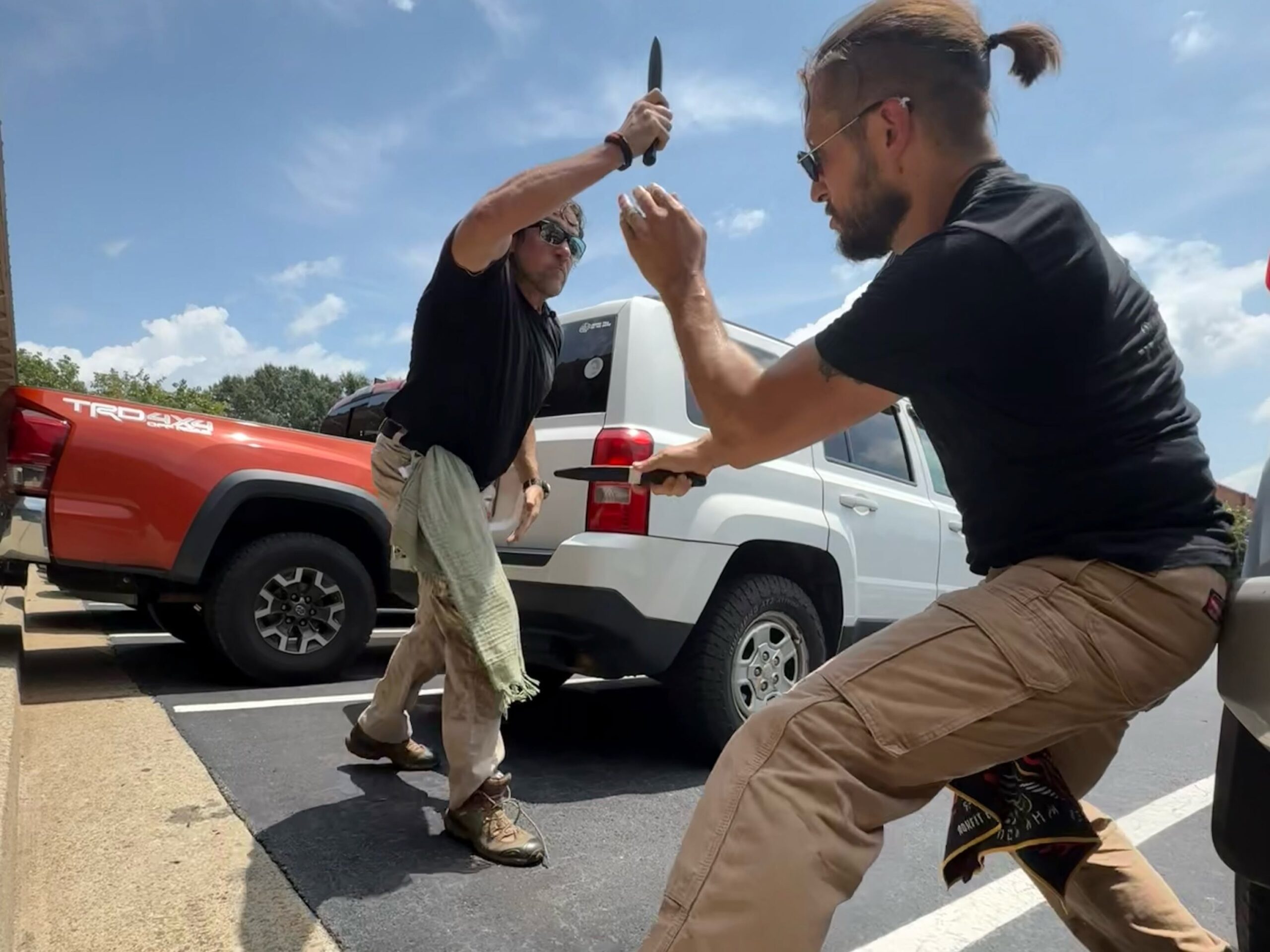 C-TAC instructors training with practice knives beside vehicles