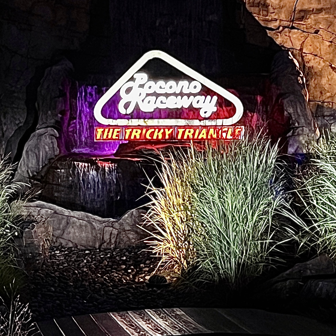 Illuminated Pocono Raceway Tricky Triangle sign at night.