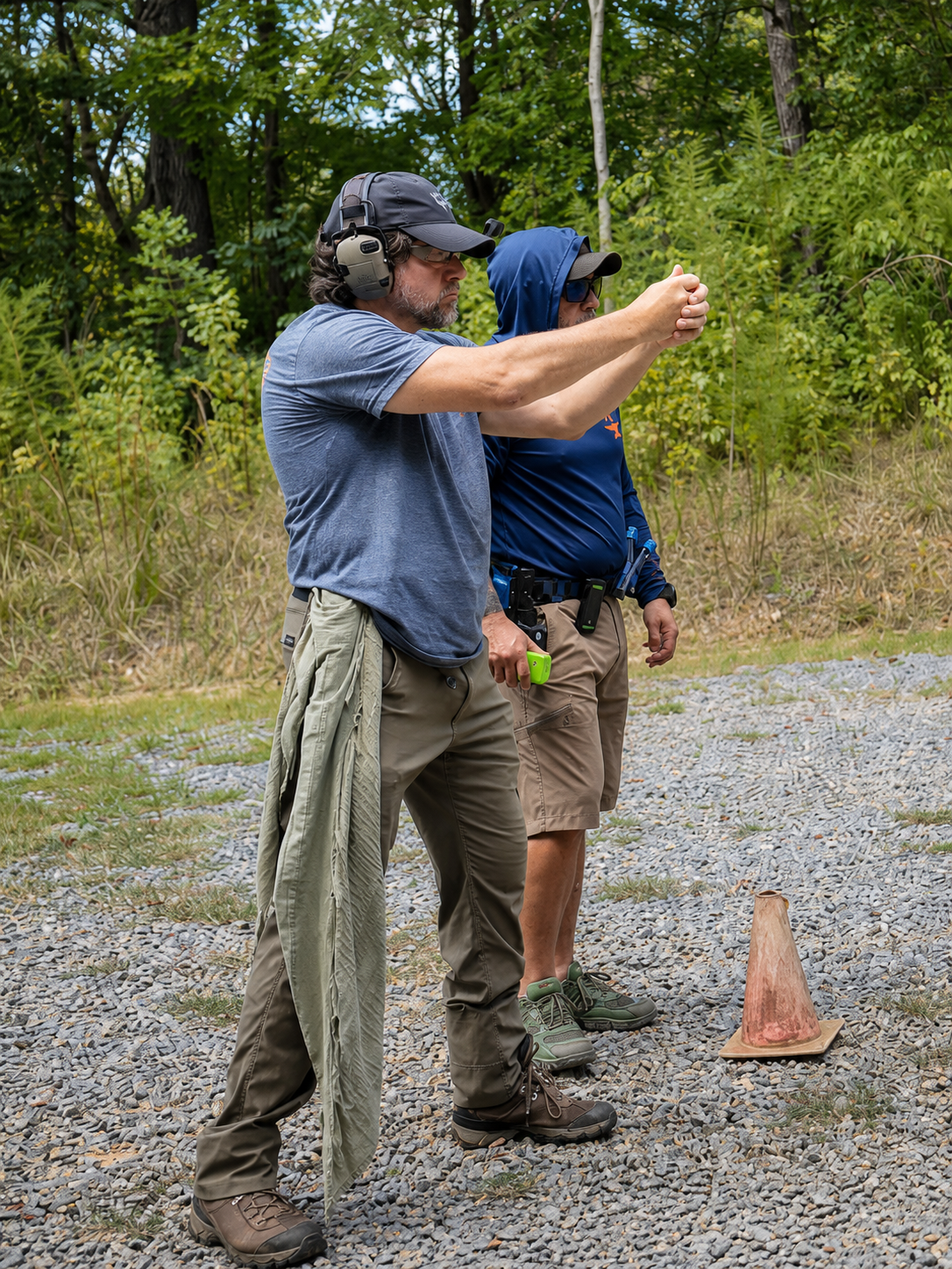 Alan Baker demonstrates an adapted two-handed grip position while Coach Dennis observes at the range.