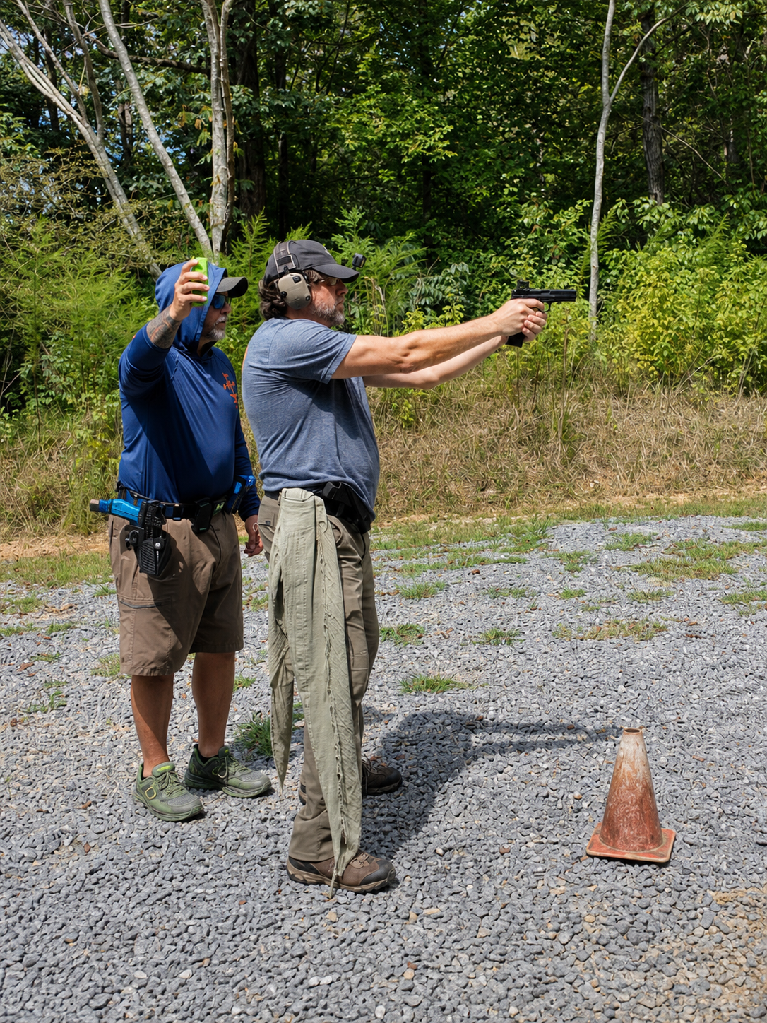 Alan Baker tests his revised handgun grip during live-fire practice as Coach Dennis observes.