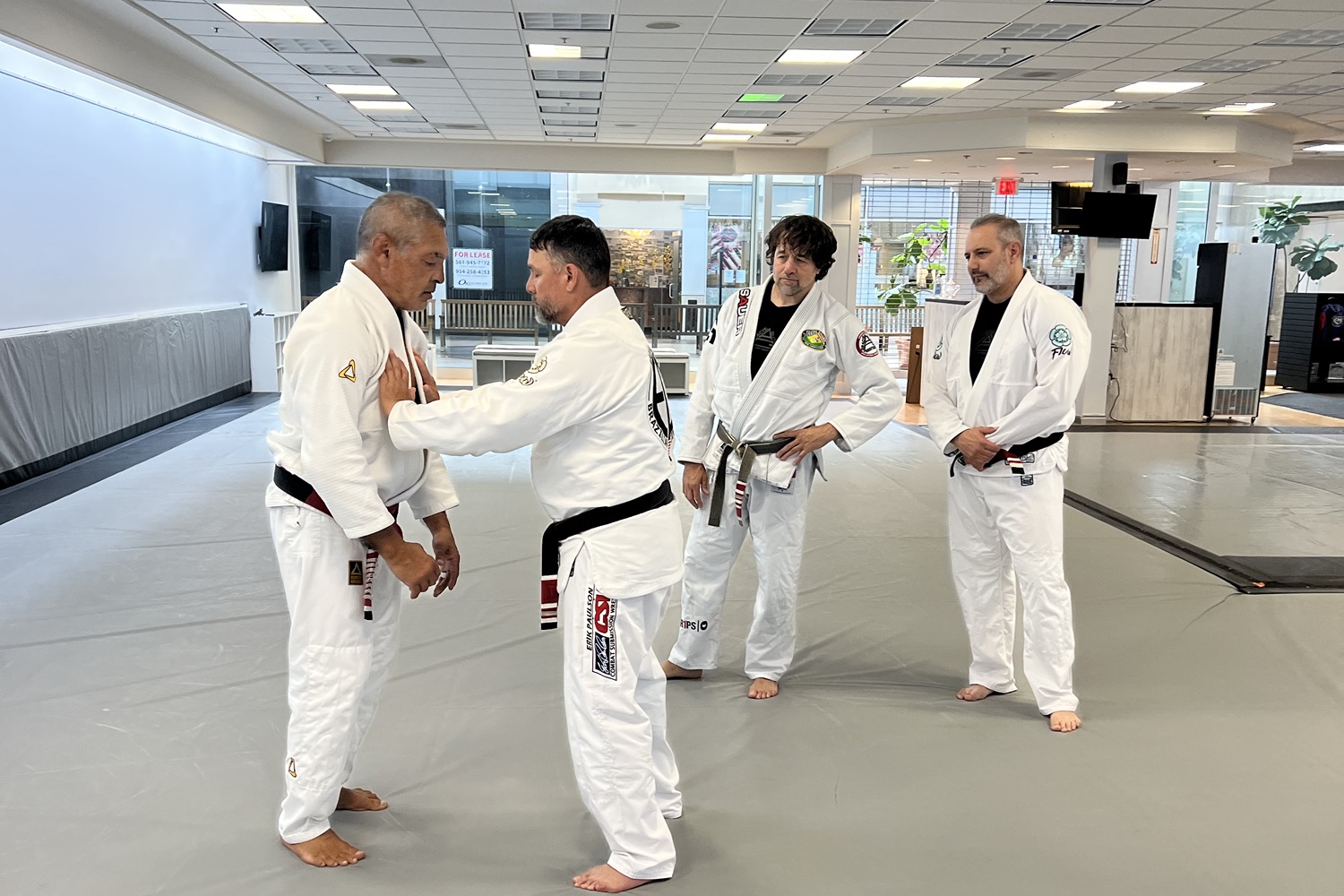 Master Rickson Gracie demonstrates a fundamental mechanical detail as Alan Baker and other practitioners observe.